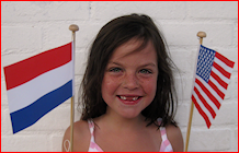 Foto van meisje met in de ene hand een Nederlandse vlaggetje en in de andere hand een Amerikaans vlaggetje