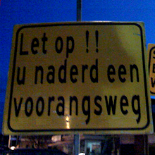 Foto langs weg met opschrift ‘U naderd een voorangsweg’ (met een foute d en een r te weinig)